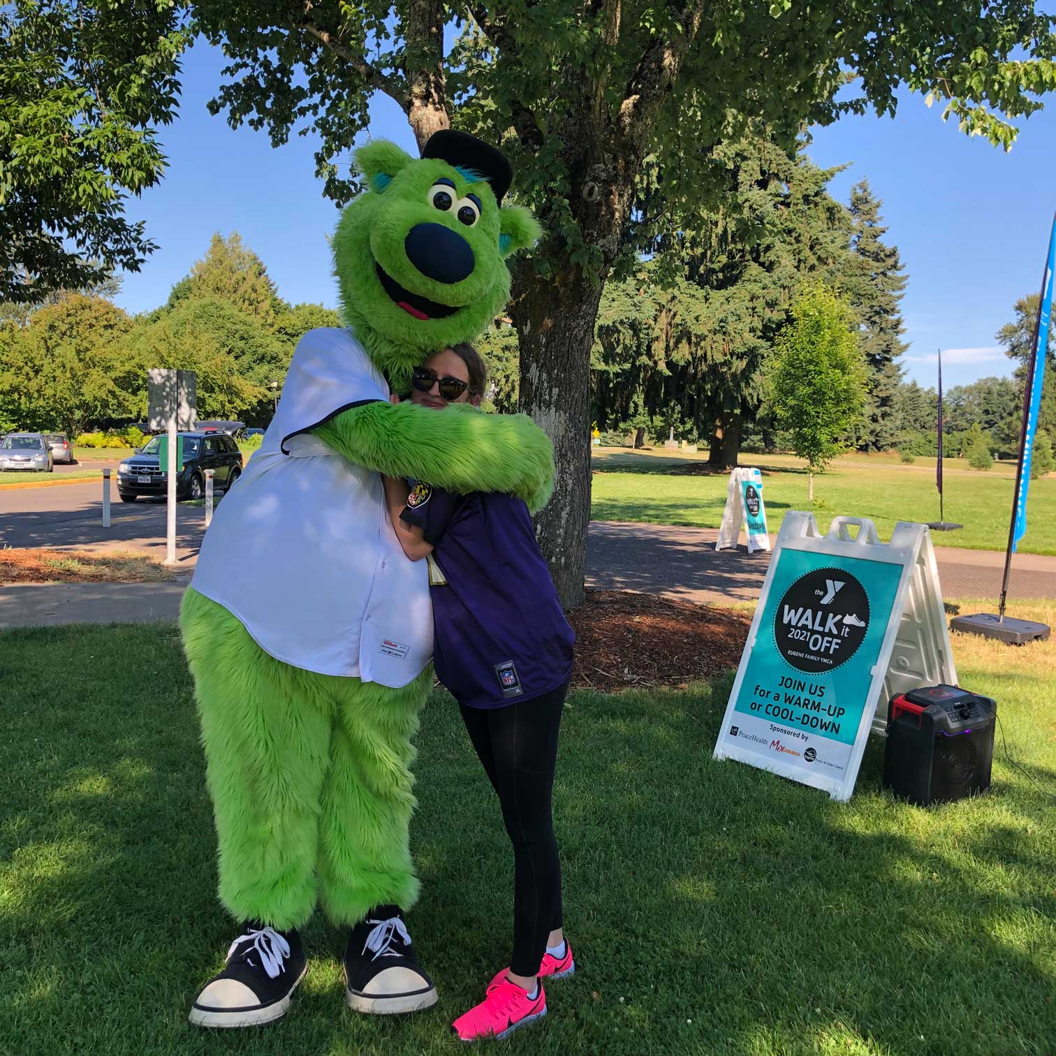 Eugene YMCA staff member hugs Eugene Emerald's mascot Sluggo