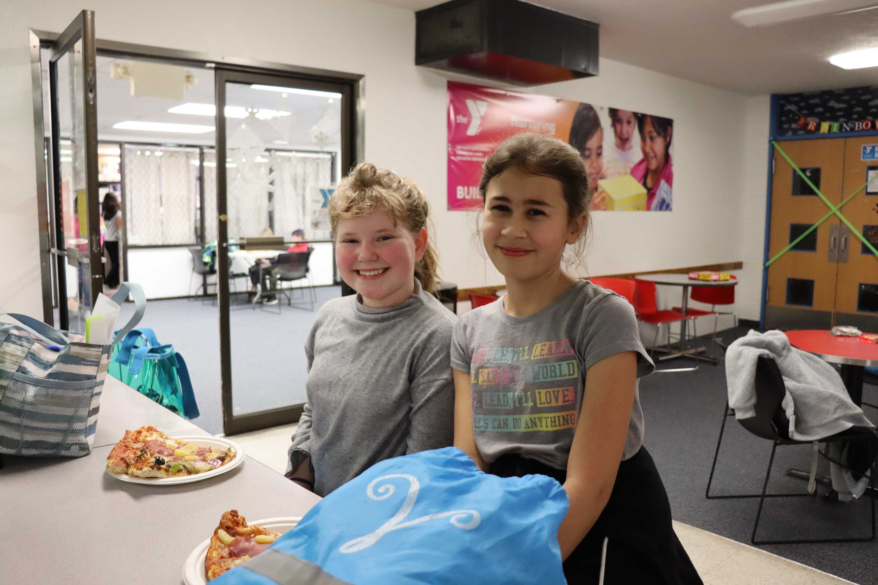 youth eat pizza in the eugene ymca lobby during middle school madness
