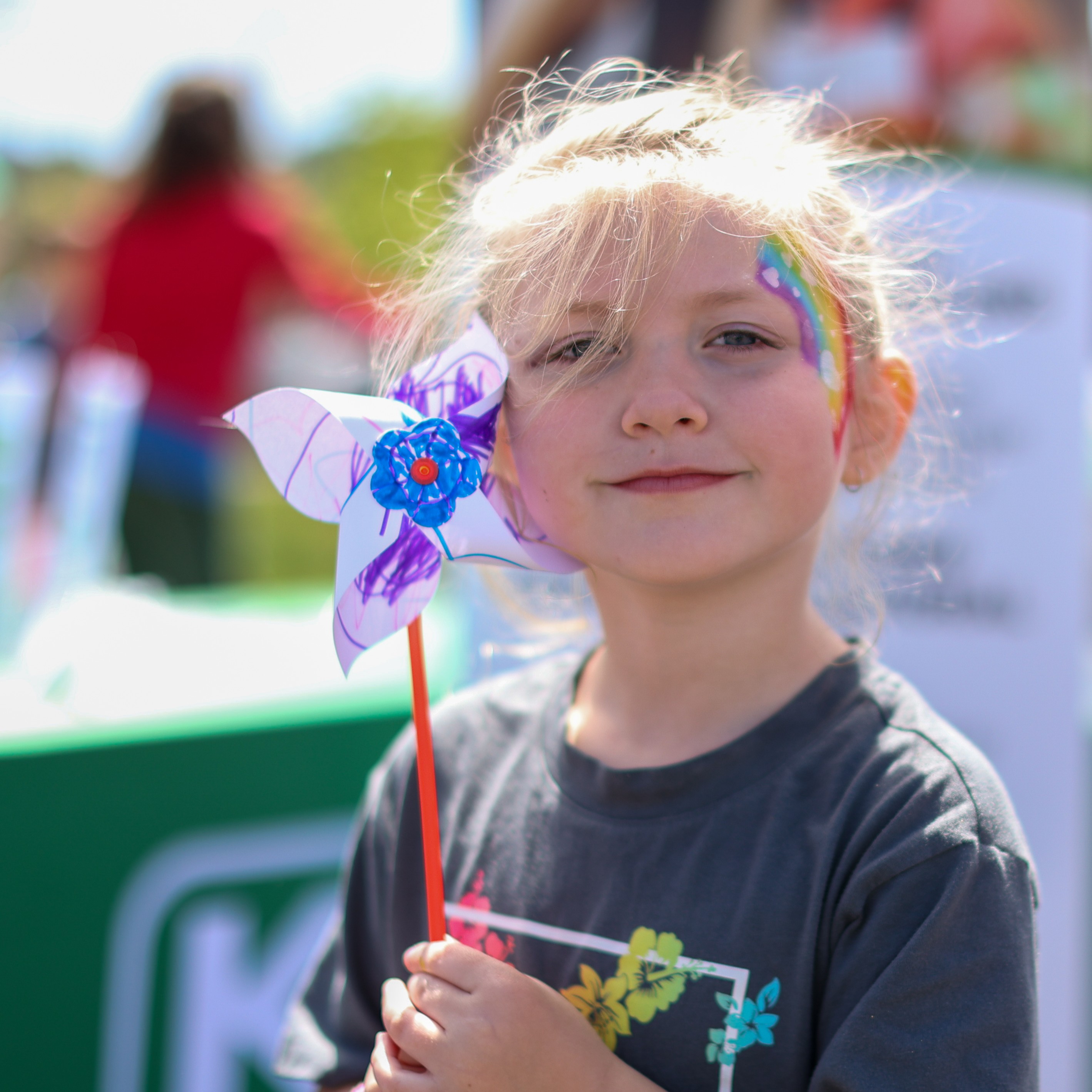 girl with painted face and pinwheel smiling