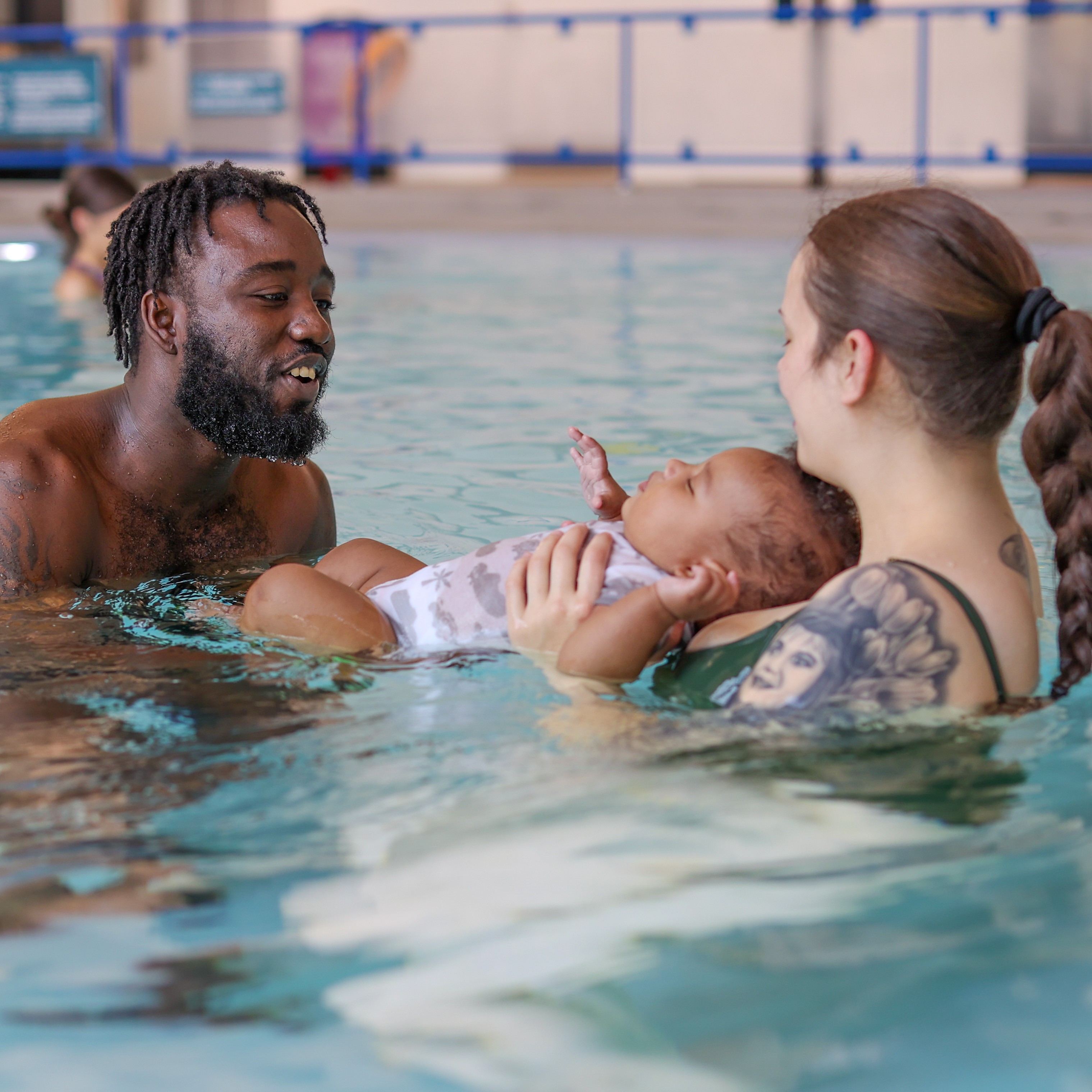 A mom, dad and baby enjoy parent and child swim lessons at the Y