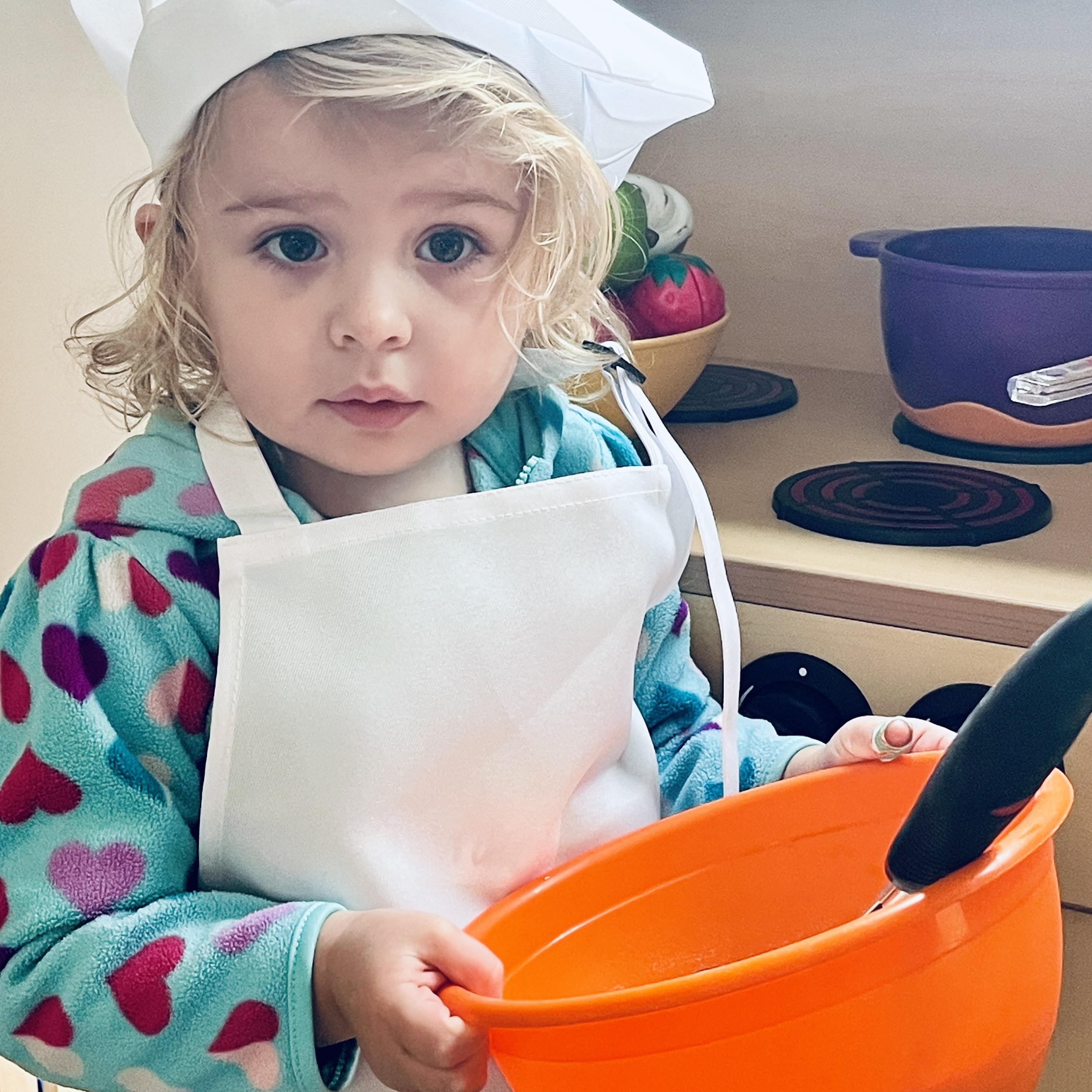 a child holding a mixing bowl and taking part in the Y's itty bitty chefs program