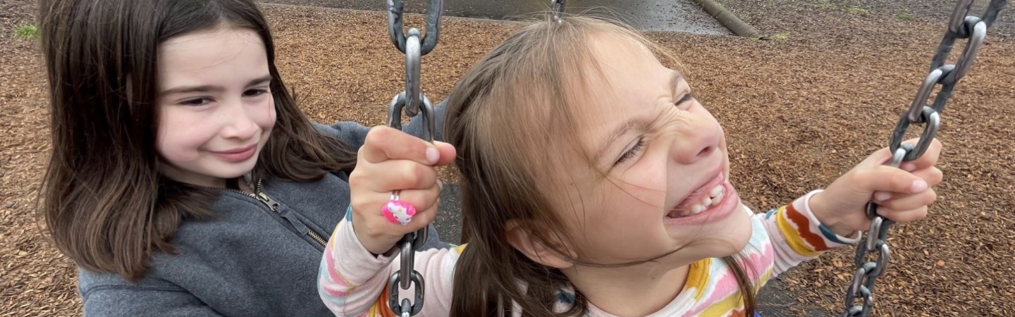 young girls swing on a tire swing on a playground after school at ymca child care