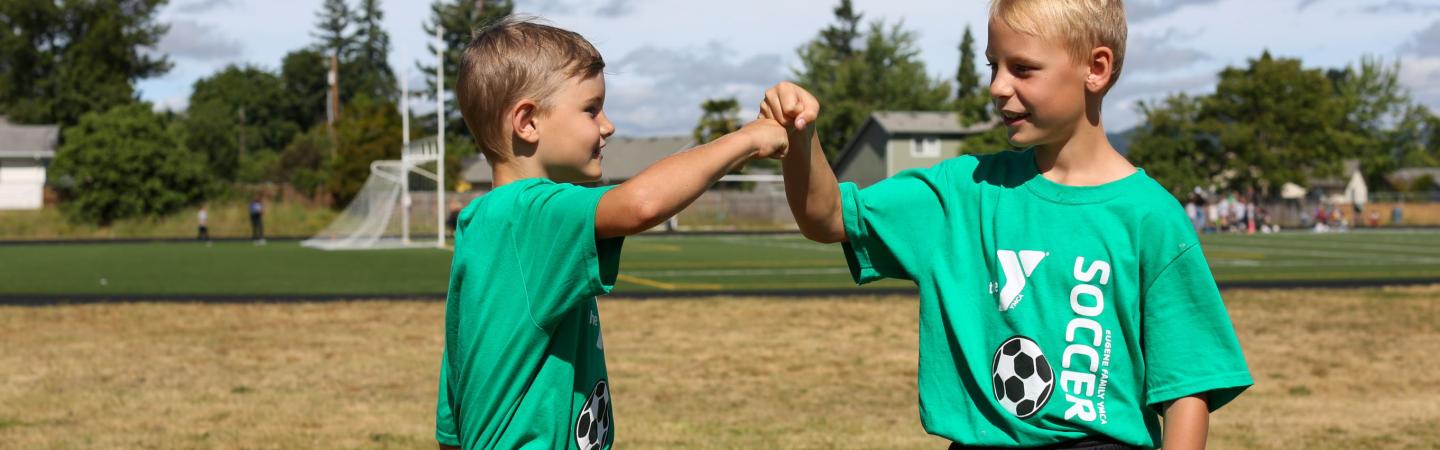 two youth fist pound during ymca soccer practice
