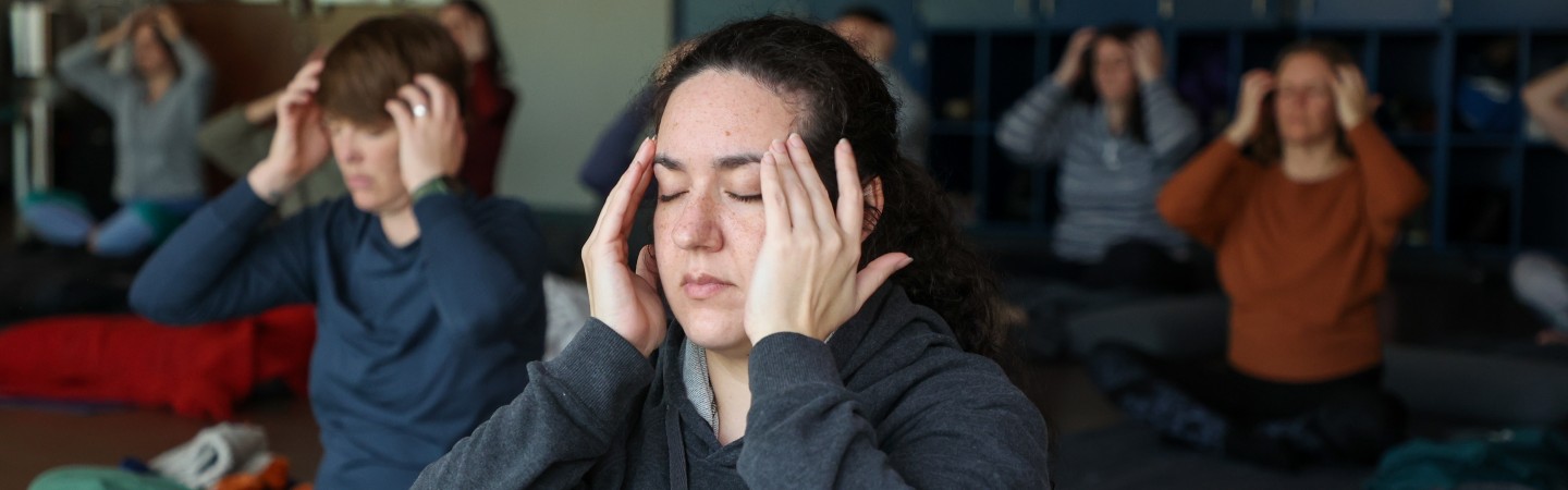 woman massages temples to de-stress in eugene ymca yoga studio