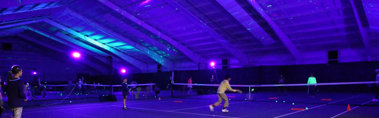 Y members play tennis at the First-Ever Glow-In-The-Dark Cosmic Tennis Night 