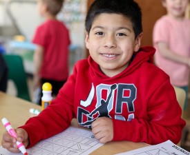a smiling boy doing a worksheet