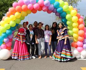 ballet folklorico colibri dancers and friends smile under balloon arch at eugene ymca welcoming festival