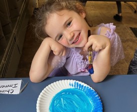 girl smiles with her art project during winter break camp at eugene ymca