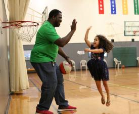 dad and daughter high five while playing basketball in eugene ymca gym