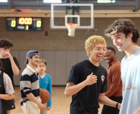 young men play basketball in a gymnasium