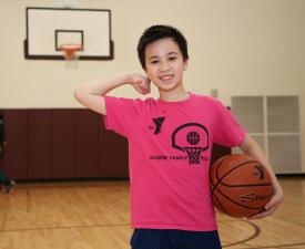 young boy plays basketball with eugene ymca