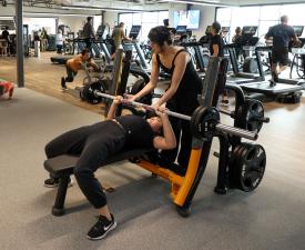 girls lift weights using barbell press in work out room