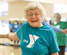 senior woman smiles at the camera while in a group fitness class
