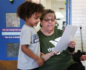 boy in ymca friends room looks at a piece of paper with his teacher