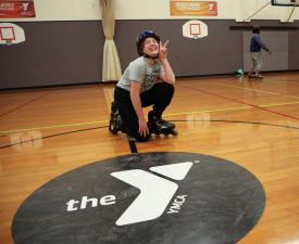 girl roller blading in eugene ymca gym shows peace sign