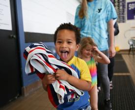 young boy sticks his tongue out on the way to swim lessons at the eugene ymca pool