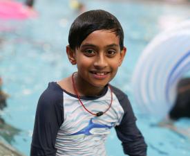 boy sitting on the edge of the pool in the eugene ymca aquatics center