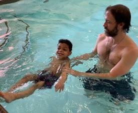 dad and son during parent child swim lessons at the ymca pool