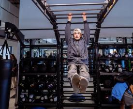 teen swings on monkey bars in gym