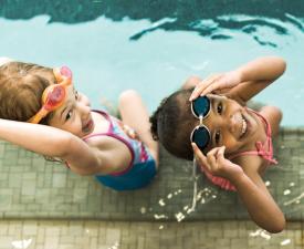 two young girls take swimming lessons at the ymca pool